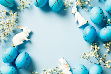 Top view photo of Easter eggs, rabbits, spring flowers on pastel blue background. Happy Easter concept.