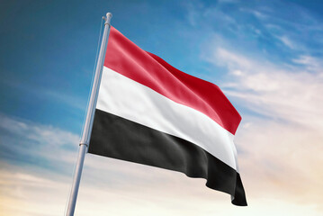 Waving flag of Yemen in blue sky. Yemen flag for independence day. The symbol of the state on wavy fabric.
