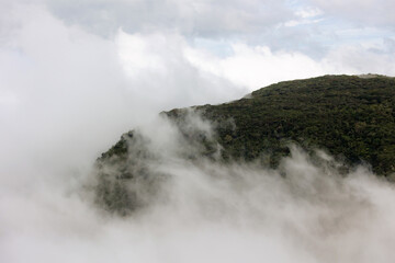 Majestic cliff adorned with native vegetation in Serra do Rio do Rastro, as the mist begins to envelop the region.