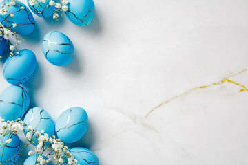 Flat lay composition with blue Easter eggs and flowers on marble stone table. Easter background.