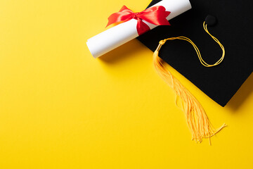 Flat lay composition with graduation cap and diploma on yellow background.
