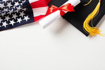 Flat lay composition with graduation cap, diploma and American flag on white background.