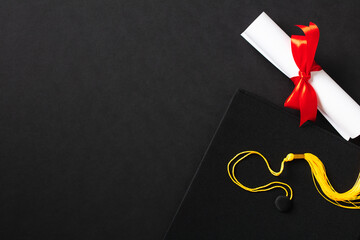 Flat lay composition with graduation cap and diploma on black background. Top view.