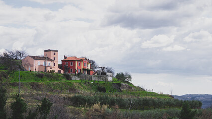 Several houses placed on a green hill in Istria on cloudy day