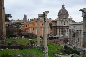 Fototapeta na wymiar Columns of the Temple of Concord, the arch of Septimius Severus and a Christian church, in the Roman forum, in Rome, Italy