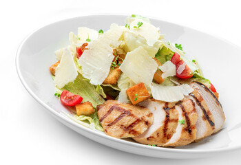 Caesar salad with grilled chicken breast, cherry tomatoes, croutons, parmesan cheese, lettuce in plate isolated on white background. Healthy food, top view