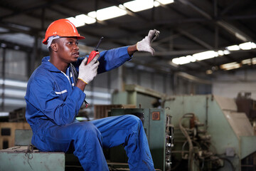 technician or foreman siting on machine talking by walkie talkie in the factory