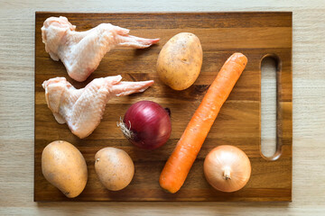Set of ingredients for preparing dinner at home. Raw chicken wings, fresh potatoes, carrots, onions...