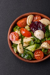 Delicious fresh caprese salad with mozzarella, tomatoes, greens with salt, spices and herbs