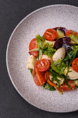 Delicious fresh caprese salad with mozzarella, tomatoes, greens with salt, spices and herbs