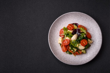 Delicious fresh caprese salad with mozzarella, tomatoes, greens with salt, spices and herbs