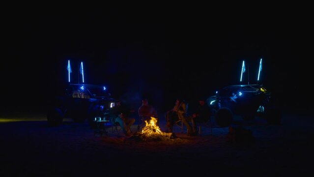 People relaxing by Campfire with UTVs