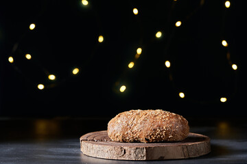 a loaf of bread is on a wooden tray with a string of lights behind it.