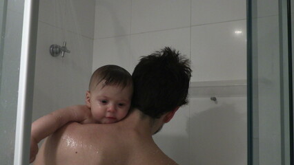 Dad holding baby son infant in shower bathing and cleaning