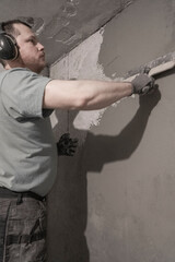 Worker Expertly Smoothes Plaster Using Spatula for Flawless Wall Finish in Room.