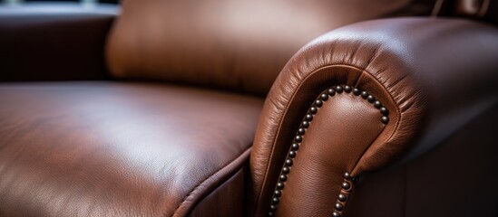 A close up shot of the arm of a brown leather chair, showing the intricate pattern of the leather and subtle detail of the metal accents, evoking a sense of comfort and luxury