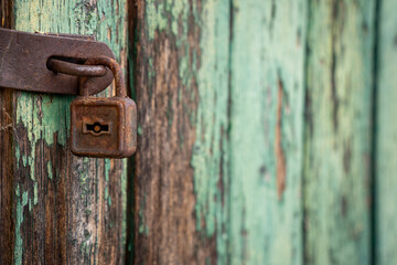 Old rusty padlock with shabby green painted wooden surface background texture