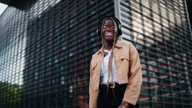 Joyful and free, young black woman listens to streaming music in city. technology allows to enjoy her favorite beats, connection and modernity to her life. Portrait of beautiful female with vitiligo
