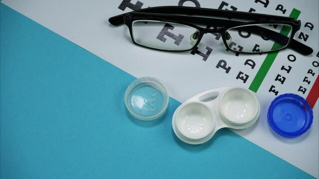 Eye Test Chart, Glasses And Contact Lenses Appear On A Blue Background. Stop motion. Top view