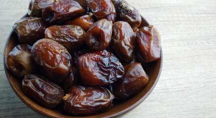 Dates fruit in a wooden bowl on a wooden background. Top view.
