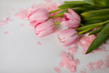 A bouquet of pink tulips and pink tinsel on a white background in the upper right corner. Copy...