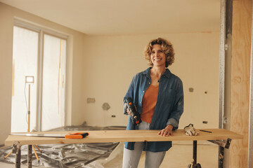 Smiling woman renovating her kitchen with DIY carpentry work - 761771452