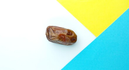 Date fruit on blue and yellow background. Top view. Copy space.