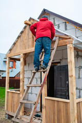 Roofer construction worker working on a roof structure at a house construction site - 761777221