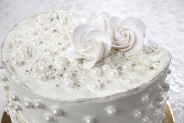 White party cake with white icing and pearls, cake design. Handmade cake made for a special celebratory occasion. Special details.