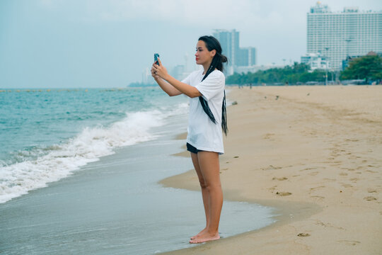 Young caucasian pretty woman taking photo with happy smile on oceanbeach 