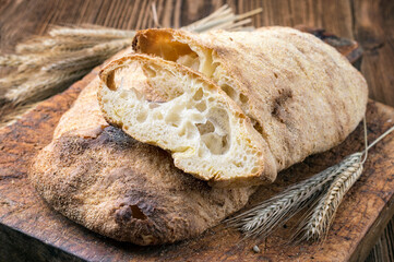 Traditional Italian ciabatta bread offered as close-up on a rustic wooden cutting board
