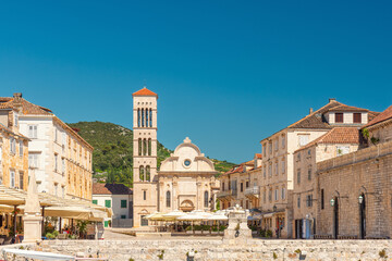 Main square Pjaca in old medieval town Hvar with Cathedral of St. Stephen, outdoors restaurants and side walk cafe on sunny day, Dalmatia, Croatia. Popular travel and tourist destination - obrazy, fototapety, plakaty