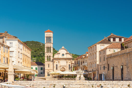 Fototapeta Main square Pjaca in old medieval town Hvar with Cathedral of St. Stephen, outdoors restaurants and side walk cafe on sunny day, Dalmatia, Croatia. Popular travel and tourist destination