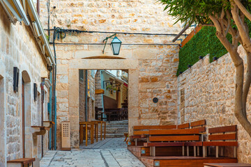 Old cozy street in the in medieval town Hvar with sidewalk cafe with nobody, Dalmatia, Croatia. Popular travel and tourist destination on summer vacations - 761782048