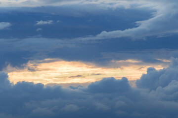Very large lush clouds in a dramatic sky, the beginning of rain, blinding sunlight visible through the gaps in the clouds