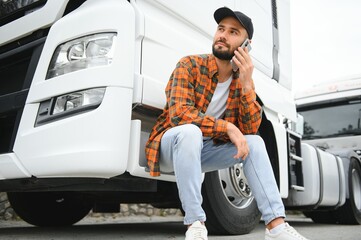 Man trucker talking on the phone by his white truck