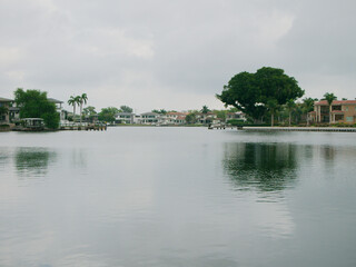 Fototapeta premium Wide angle view across Coffee Pot Bayou looking east in Saint Petersburg, FL. Cloudy day sky calm water. With green trees on sides, houses and boat docks on the back side of the bay . Room for copy. 