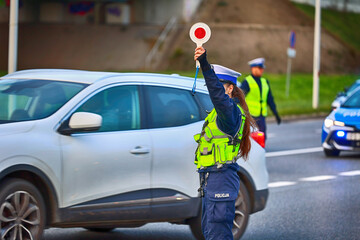 Policjantka ruchu drogowego z lizakiem podczas zatrzymania pojazdów na drodze z tarczą do...