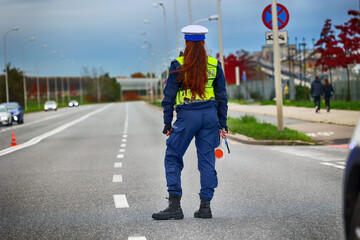 Policjantka ruchu drogowego z lizakiem podczas zatrzymania pojazdów na drodze z tarczą do zatrzymywania.
