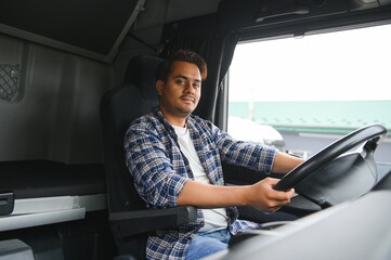 A young Indian male truck driver sits behind the wheel