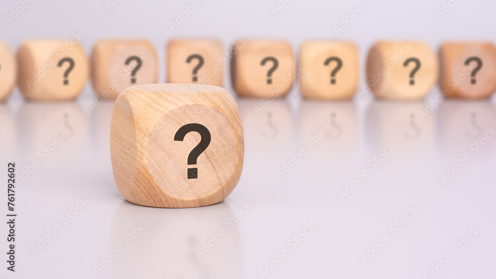 Poster in the foreground is one wooden cube with a question mark and a reflection from the table surface. i