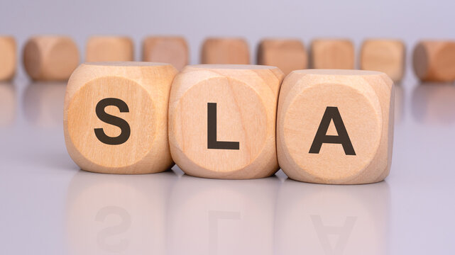 the image depicts three wooden blocks with the letters 'SLA' in focus, reflecting on the table surface. in the background, there is a row of wooden blocks, blurred and out of focus