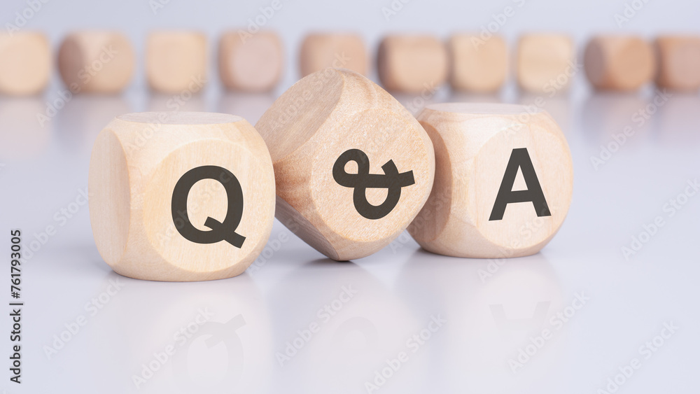 Aufkleber the text 'q and a' - question and answer - on wooden cubes, positioned on an office desk, implies an