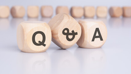 The text 'Q and A' - Question and Answer - on wooden cubes, positioned on an office desk, implies an emphasis on interactive communication and problem-solving