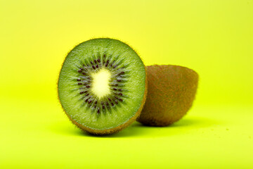 Pieza de fruta kiwi cortado por la mirad sobre fondo amarillo