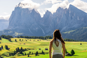 woman with her back watching the mountains from the green meadow