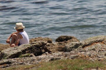 enfant assis sur les rocher regardant la mer (format paysage)