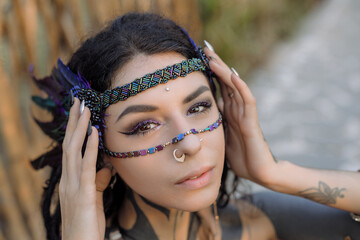 A woman is sporting a headband with feathers and a nose ring
