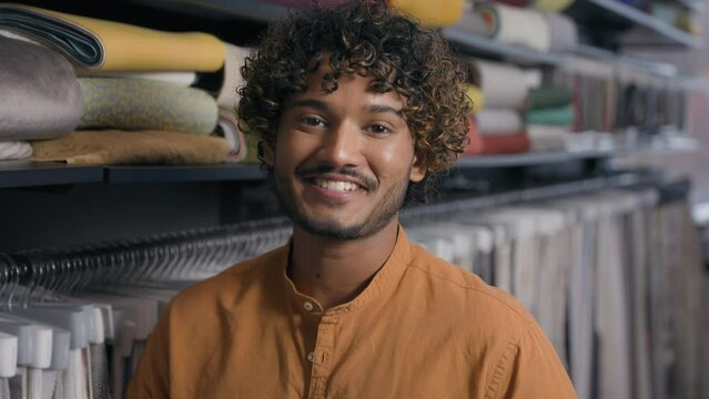 Arabian Indian ethnic man customer salesman fashion designer tailor stylist in fabric shop textile store happy male owner small business atelier tailoring clothes cloth shooping guy smiling at camera