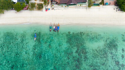 Aerial view of traditional Thai long tail boats at a beach at Koh Phi Phi island, Krabi, Thailand. Tropical paradise white sand beach with no people, turquoise waters of Andaman sea. 